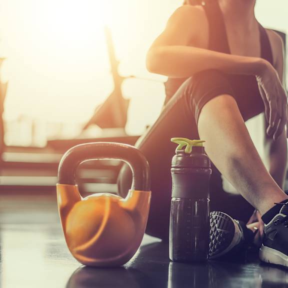 A person is sitting on the floor with a kettlebell and a shaker bottle in front of them. at Park Lamont Apartments & Townhomes, Ohio