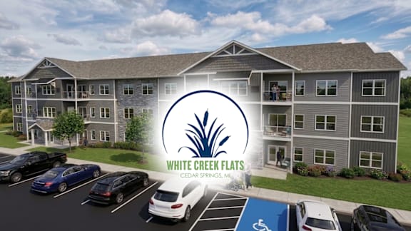 A large building with a parking lot in front of it and a sign that says White Creek Flats.