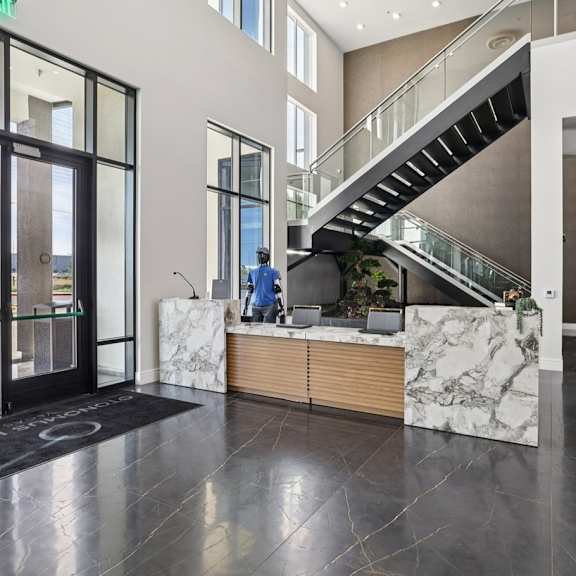Lobby area with marble counter and glass staircase and robot greeter