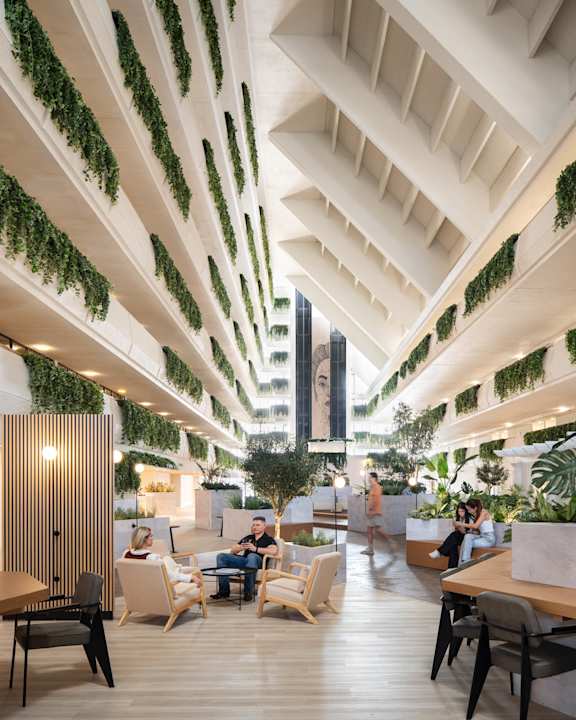 A modern cafe with wooden tables and chairs and green plants hanging from the ceiling.