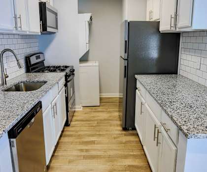 an empty kitchen with white cabinets and a black refrigerator