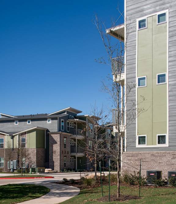 A modern apartment complex with a well-maintained lawn in front.