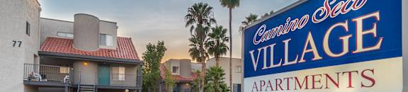 Blue and white lit sign on top of bricks, buildings in background