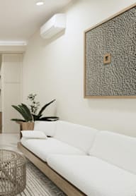 A living room with a white couch, a television, and a wooden cabinet.