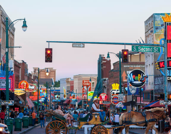 a city street filled with people and horse drawn carriages
