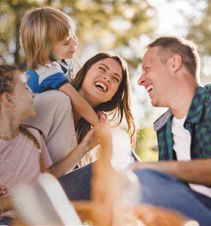 A family of four is sitting together outside enjoying a sunny day.