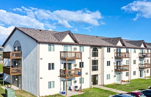 Apartment complex with white buildings and balconies under a blue sky.