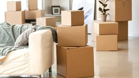 A living room with a couch and stacks of cardboard boxes.