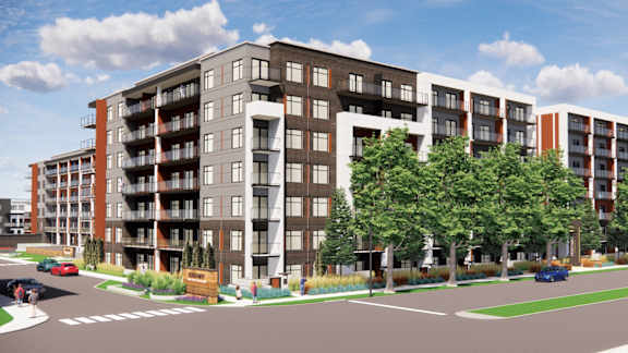 A modern apartment complex with a parking lot in front.