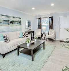 A living room with a white couch, a coffee table, and a painting on the wall.
