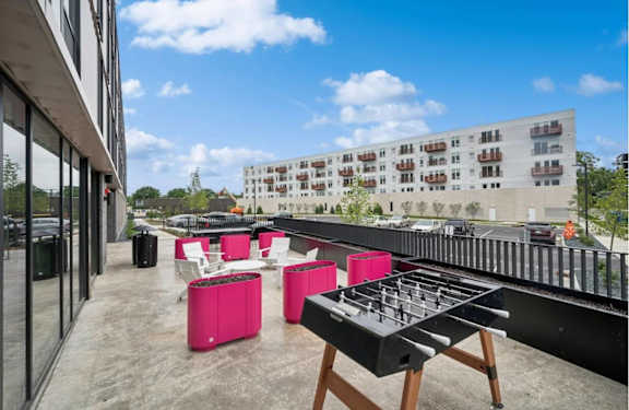 a rooftop patio with a barbecue grill and pink furniture