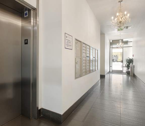 A hallway with a chandelier, a plant, and a wall with a window.