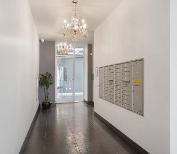 A long hallway with a chandelier and a plant.