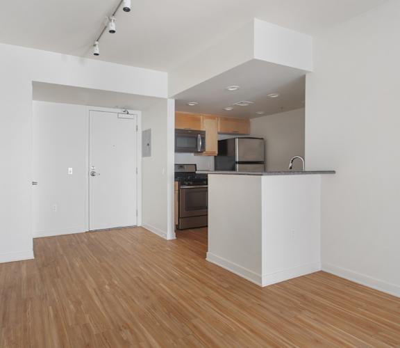 A kitchen with a white counter and wooden floors.