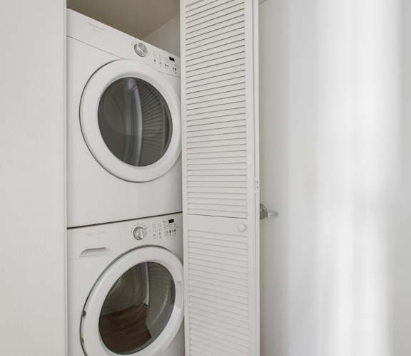 Two white front loading washing machines in a laundry room.