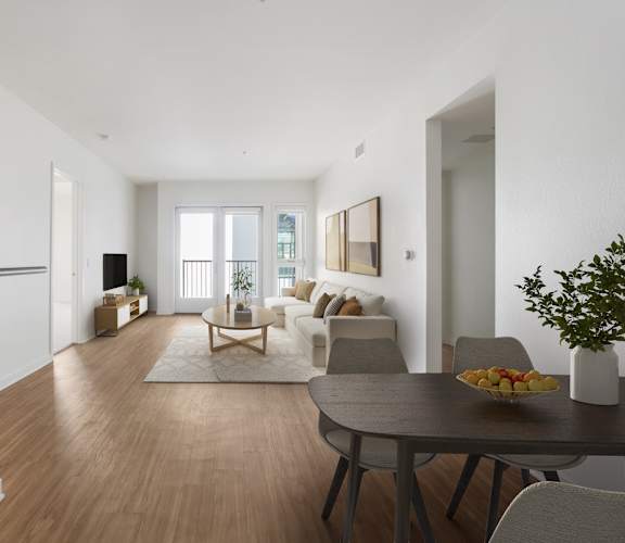 A modern dining room with a wooden floor and a table set with a bowl of fruit.