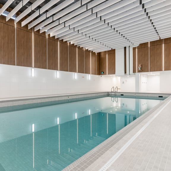 a large indoor swimming pool with a white tile floor and wooden walls