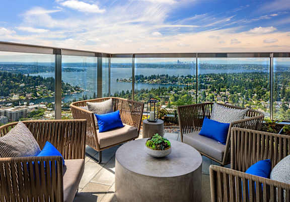 a patio with chairs and a table on a balcony overlooking a city and the ocean at Two Lincoln Tower Apartments, Bellevue, WA, 98004