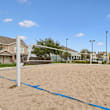 A sandy beach volleyball court with a net and a few blue lines on the sand.