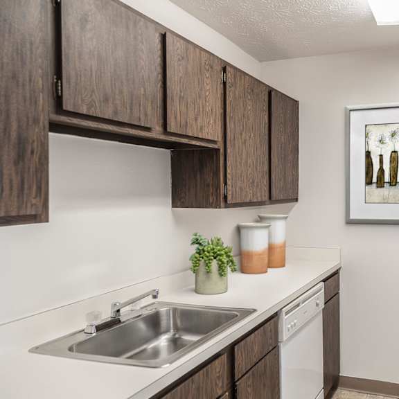A kitchen with a white fridge, brown cabinets and a painting of bottles on the wall at Hummingbird Pointe & The Gardens, Ohio 44129