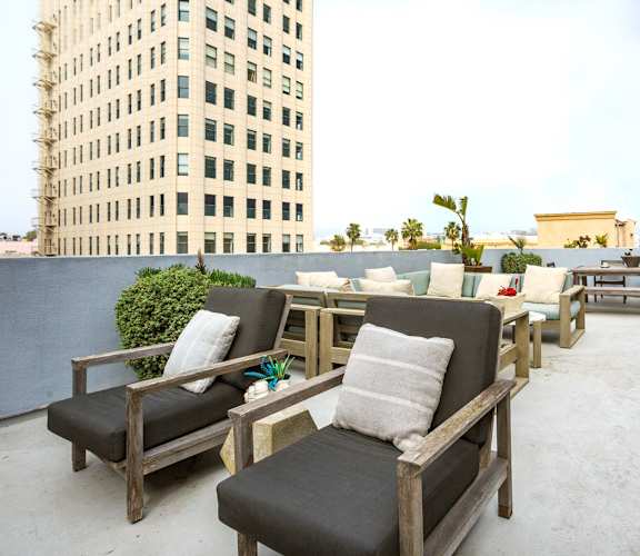 A patio with wooden furniture and a tall building in the background.