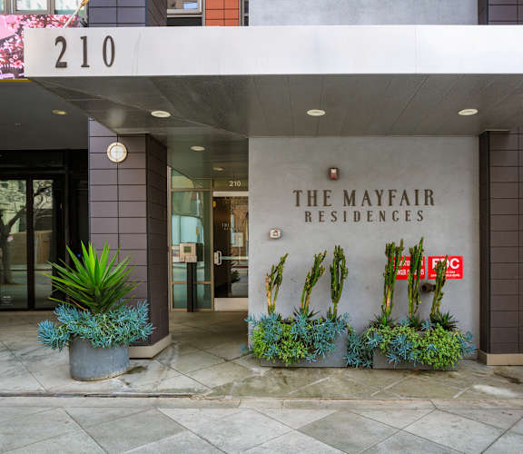 The Mayfair Residences building with a sign and plants in front.