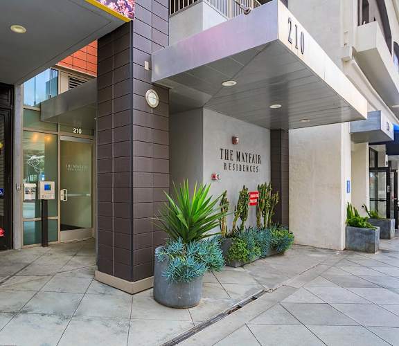 The Mathew Residences building with a glass door and a plant in front.