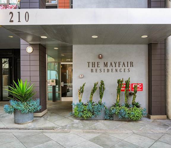 The Mayfair Residences building entrance with a sign and plants.
