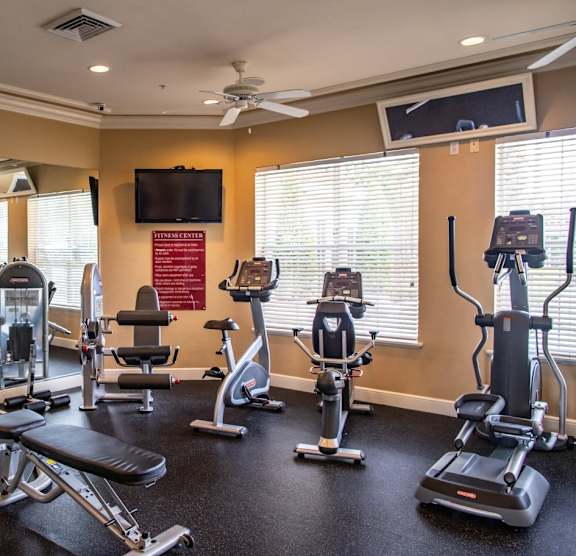 A gym with a variety of equipment including treadmills, stationary bikes, and weight racks. at Northlake Park Apartments, Orlando, Florida