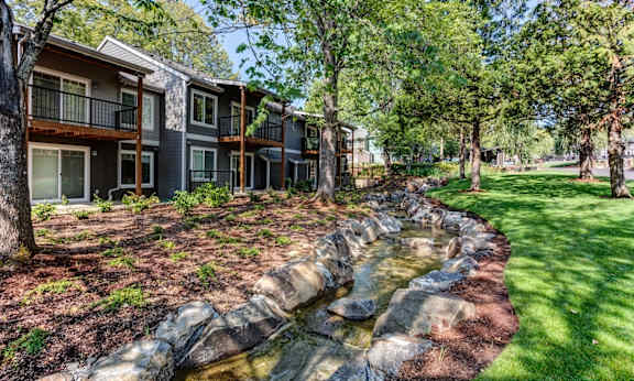 A stream flows through a landscaped area in front of a building at Commons at Redwood Creek Apartments, Beaverton, 97008