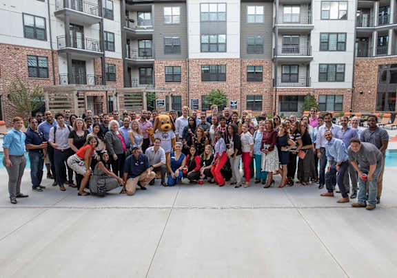 a group of people posing for a picture in front of an apartment building