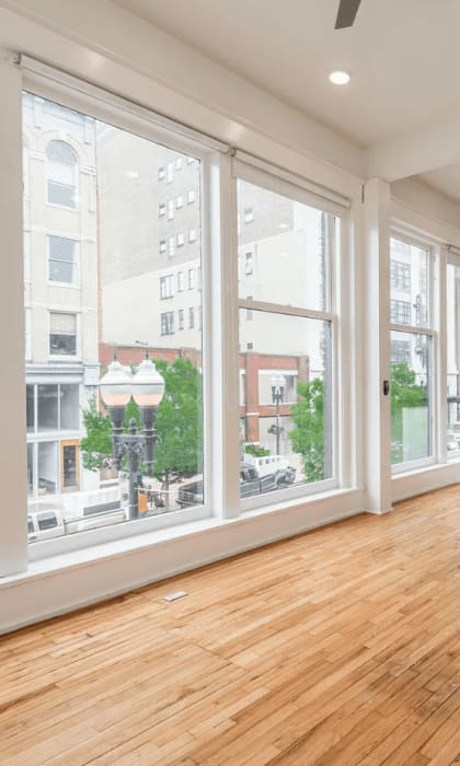 a living room with a large window and hardwood floors