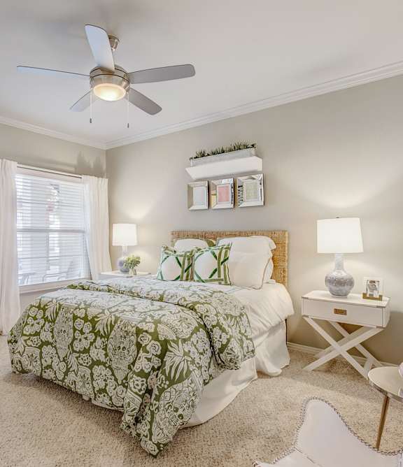 A bedroom with a bed, a nightstand, and a chair.