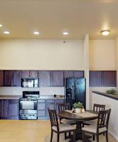 A kitchen with dark brown cabinets and a black refrigerator.