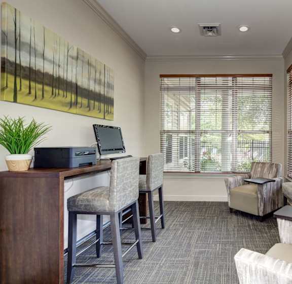A room with a desk, chairs, and a painting on the wall.