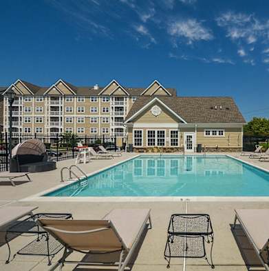 a swimming pool with chairs and a building in the background