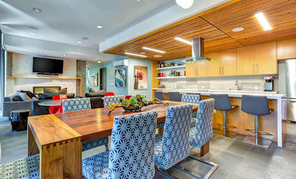 a kitchen with a long wooden table and blue chairs
