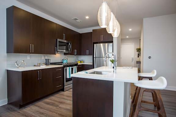 A modern kitchen with dark brown cabinets and a white countertop.