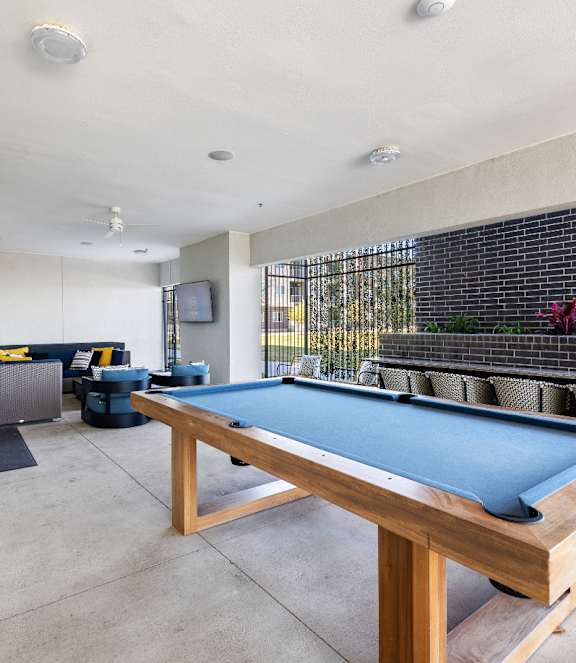A pool table in a room with a TV and a couch.