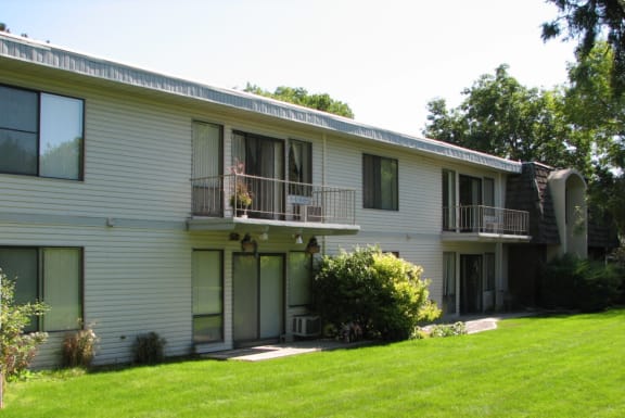 the front of a white house with a green lawn and a balcony