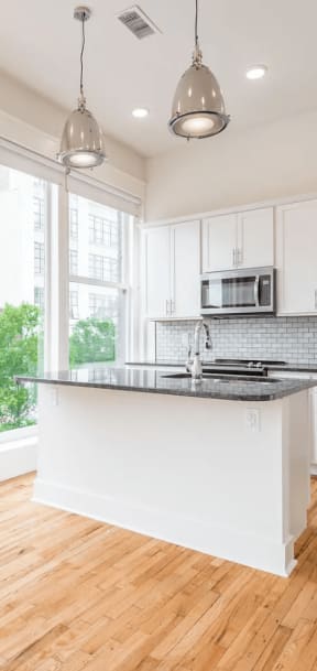 an open kitchen with a large window and hardwood floors