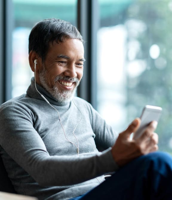 Man smiling at phone while listening to music