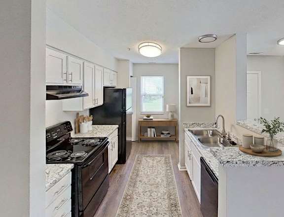 A kitchen with a black refrigerator and a white counter top. at Arbors at Hickory Creek Apartments , Illinois