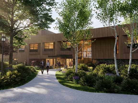 A modern building with a curved wooden exterior and a pathway leading to it.