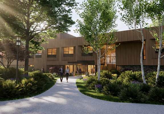 A modern building with a curved wooden exterior and a pathway leading to it.