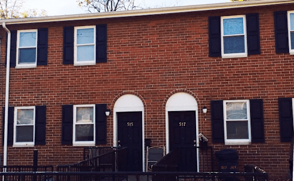 A red brick house with black shutters and a black door.