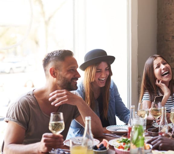Friends Laughing While Having Food and Drinks Together