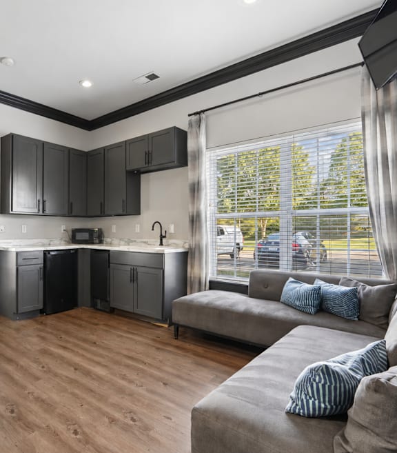 A kitchen with black cabinets and a wooden floor.