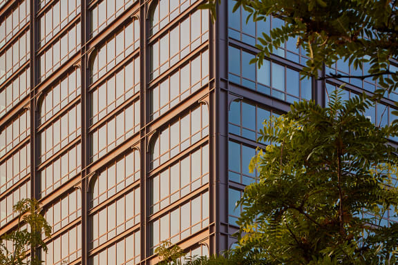a tall glass building with trees in the foreground