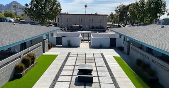 A courtyard with a black bench in the middle of it.